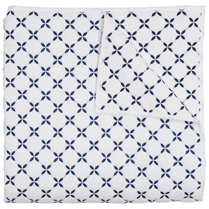 The Layla Indigo Coverlet by John Robshaw is a folded white cotton voile coverlet, hand quilted with a navy geometric pattern inspired by Mughal gardens, featuring circular four-petal motifs.