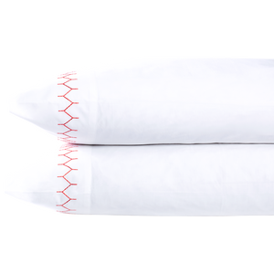 Two white John Robshaw Stitched Coral Pillowcase Pairs are stacked, each made of pure cotton percale and featuring a decorative red zigzag stitch along the edge.