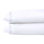 Two Stitched Light Indigo Pillowcases by John Robshaw, crafted from soft cotton percale with a blue zigzag embroidered edge, are stacked on a white background.