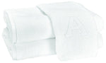 Two Auberge Monogram Bath Towels by Matouk—folded white cotton terry, one with an embroidered "A"—are stacked on a white background, adding elegant charm to any guest bath.