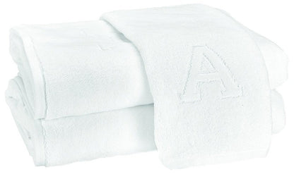 Two Auberge Monogram Bath Towels by Matouk—folded white cotton terry, one with an embroidered "A"—are stacked on a white background, adding elegant charm to any guest bath.