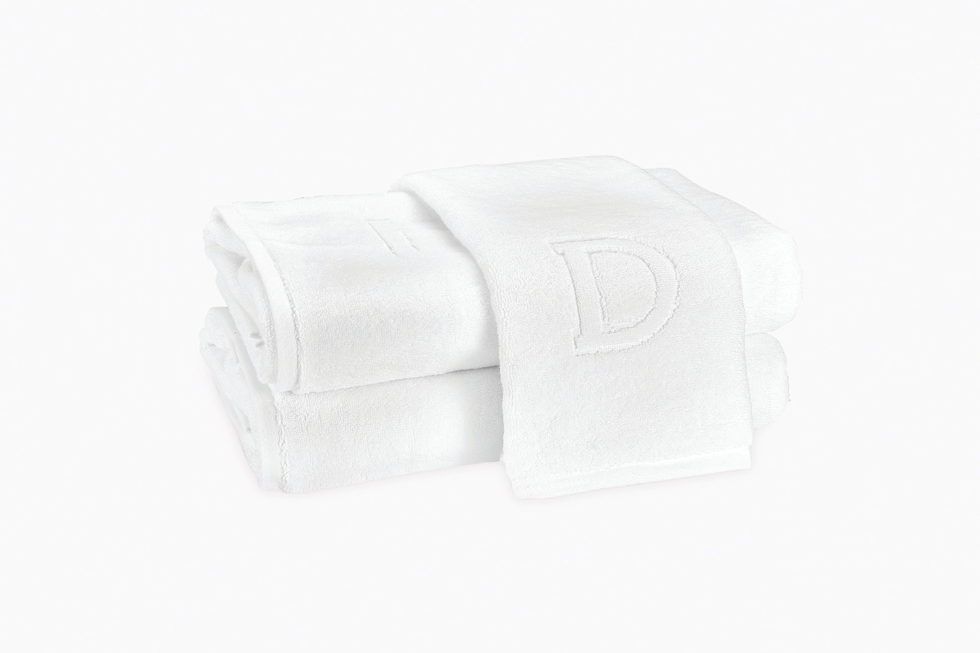 Two folded white Auberge Monogram Bath Towels by Matouk are stacked neatly, one featuring an embroidered letter "D"—ideal for bringing a personalized touch to your guest bath or creating an upscale, retreat-inspired setting.