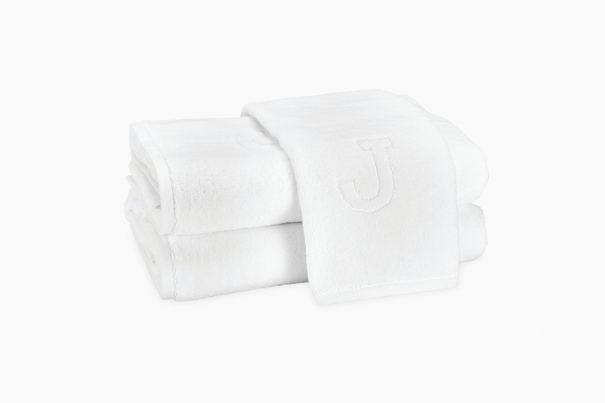 Two neatly folded Matouk Auberge Monogram Bath Towels, one draped on top and featuring an embossed "J," bring a touch of elegance to your guest bath.