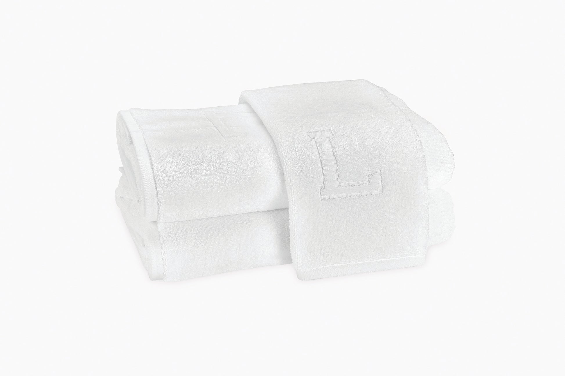 Two crisp white Matouk Auberge Monogram Bath Towels, one atop the other with a large embroidered "L," add a refined touch of hotel style to your guest bath.