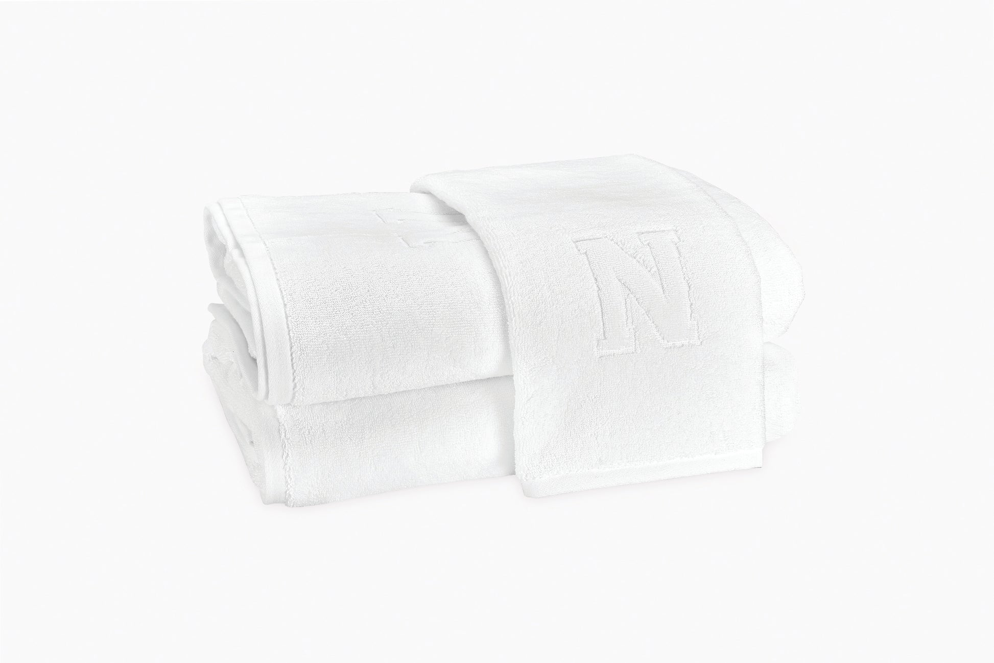 Two folded Matouk Auberge Monogram Bath Towels with a large embroidered "N" are displayed on a plain white background—ideal for the guest bath.