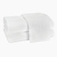 Two folded Auberge Monogram Bath Towels by Matouk, made of white cotton terry with an embroidered "T," ideal for an Auberge-inspired guest bath, shown on a plain white background.