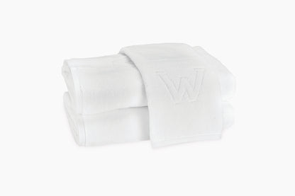 Two folded Matouk Auberge Monogram Bath Towels, stacked with a visible embroidered "W" on the top towel, set against a plain white background—an elegant touch for any guest bath.