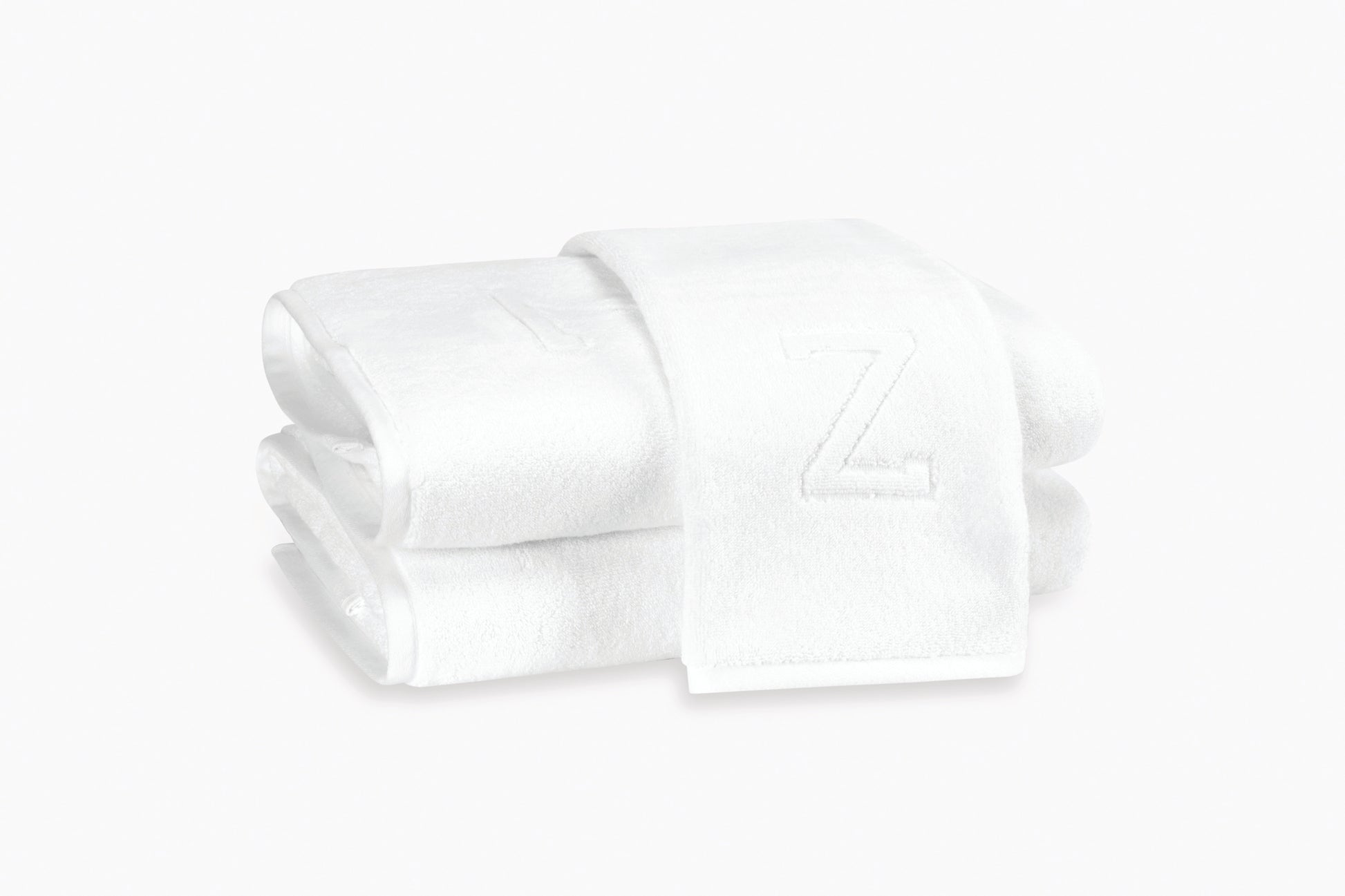 Two white Matouk Auberge Monogram Bath Towels are stacked neatly, ideal for the guest bath, with the top towel featuring an embroidered letter "Z".