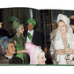 Attendees in vibrant, ornate costumes at a social gathering, channeling the Romanov dynasty's grandeur with turbans and headpieces, hold drinks and smile in a room reflecting Art Deco Paris, as featured in Assouline's "Legendary Costume Balls of the Twentieth Century.