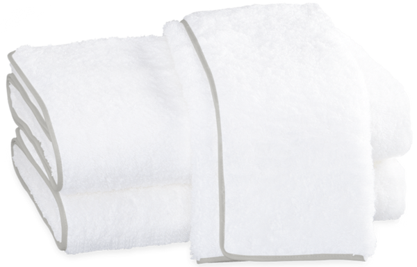 Two white, fluffy Matouk Cairo Bath Collection - Silver bath towels made of plush cotton terry neatly folded and stacked on a white background.