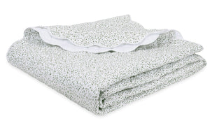 The Celine Bedding Collection in Grass by Matouk features a folded white Egyptian cotton percale blanket with green dots and an embroidered scalloped edge, neatly stacked on a white surface.