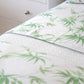Close-up of a neatly made bed featuring Matouk’s Basketweave Bedding Collection in white, shown next to a white dresser with a silver knob.