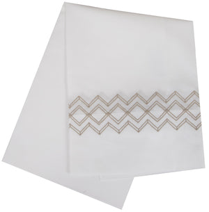 Two white folded towels, made from luxurious Egyptian cotton, have a beige geometric zigzag embroidery along the edge. They perfectly complement the HIVE Exclusive Arezzo Bedding Collection in Camel by Matouk and are OEKO-TEX certified for comfort and safety.