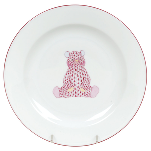 The Bear Plate, Pink by Herend is crafted from porcelain with a red rim and features a charming pink and red bear illustration in the center with hand-painted details.