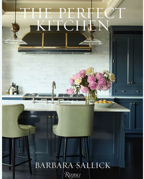 Cover of "The Perfect Kitchen" by Rizzoli displays a stylish kitchen with green chairs, blue cabinets, marble backsplash, and pink flowers—capturing timeless kitchen design inspiration.