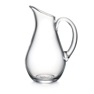The Simon Pearce Woodstock Glass Pitcher, Large, is part of the Woodstock Collection and features a curvaceous spout and handle, perfect for serving chilled white beverages.