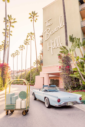 Gray Malin’s The Beverly Hills Hotel, White Frame (29.5" x 41.5"), features a vintage blue convertible and luggage cart amid palm trees, evoking timeless glamour in this captivating artwork.