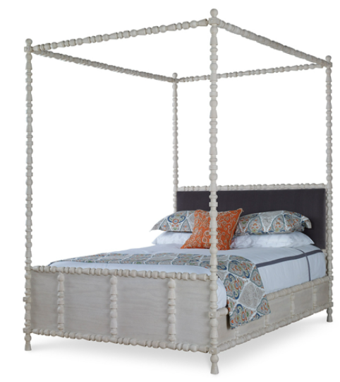 The St. Tropez Linen King Canopy Bed by Mr Brown features a white rustic pine frame with intricate carved details. It comes with vibrant patterned bedding and is complemented by a square orange accent pillow. Unfortunately, the product description lacks dimensions and contextual details to effectively highlight its key features or benefits.