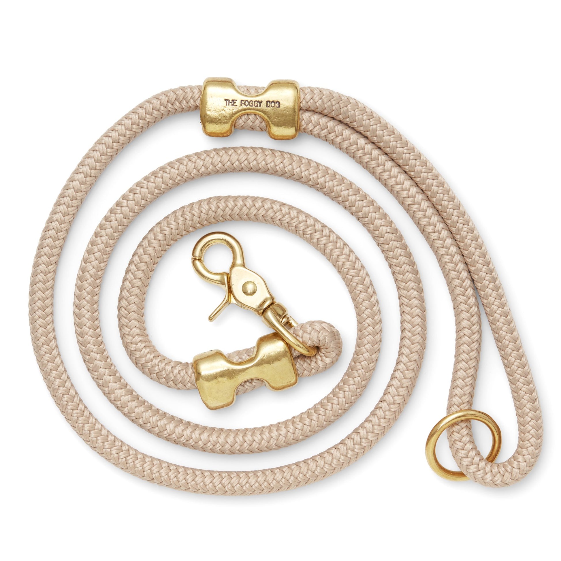 The Foggy Dog’s Marine Rope 5' Dog Leash features beige braided rope, gold hardware (clasp, ring, and bone-shaped accent), and pairs stylishly with a pink collar—perfect for chic walks or outings to the dog park.