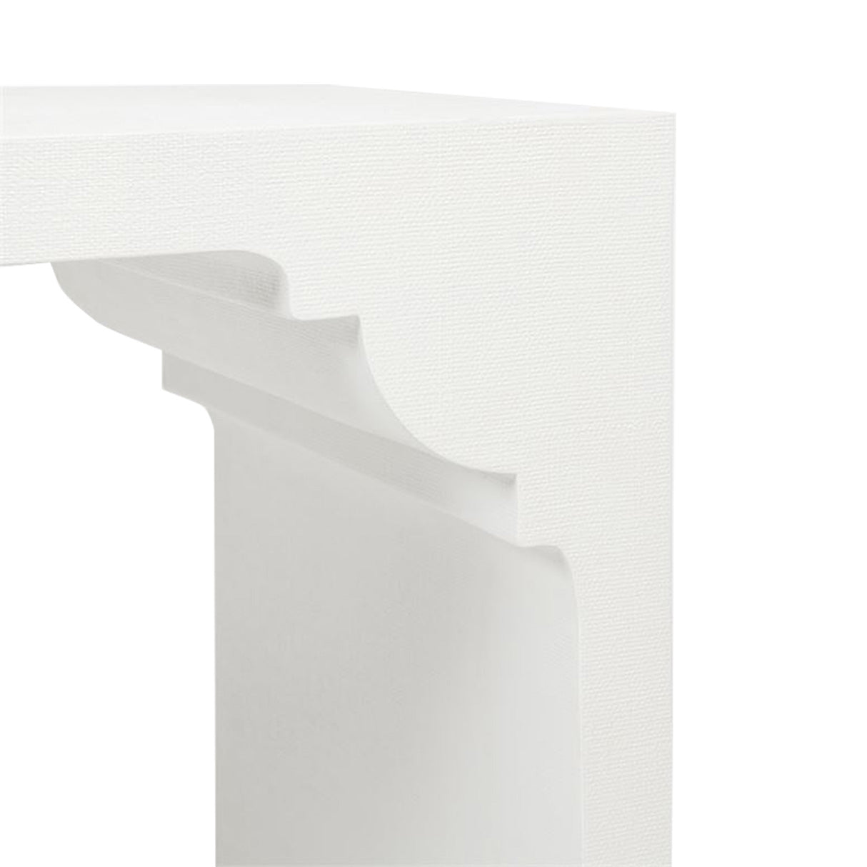 Close-up view of a corner of a white minimalist table with curved detailing underneath the tabletop, reminiscent of the Felton Designer White Console in Faux Jute by Made Goods.