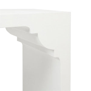 Close-up view of a corner of a white minimalist table with curved detailing underneath the tabletop, reminiscent of the Felton Designer White Console in Faux Jute by Made Goods.