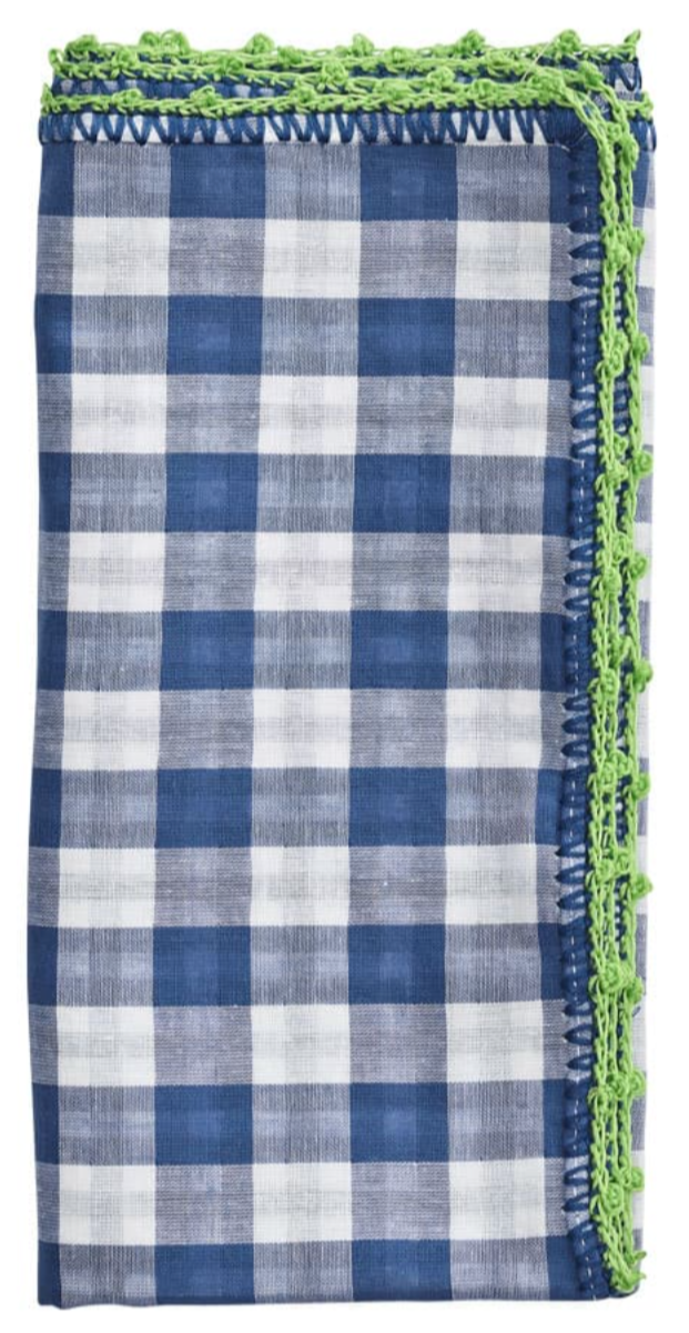 The Kim Seybert Gingham Check Napkin Set features neatly folded cotton napkins with a blue checkered pattern, each accented by a delicate green crochet edge.