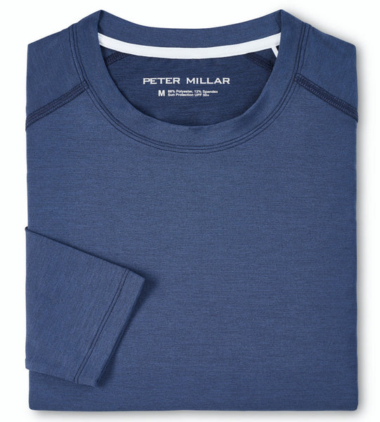Folded blue Peter Millar Performance T-Shirt with visible brand label "Peter Millar" on the collar, featuring UPF 50+ sun protection, size medium, displayed on a flat surface.