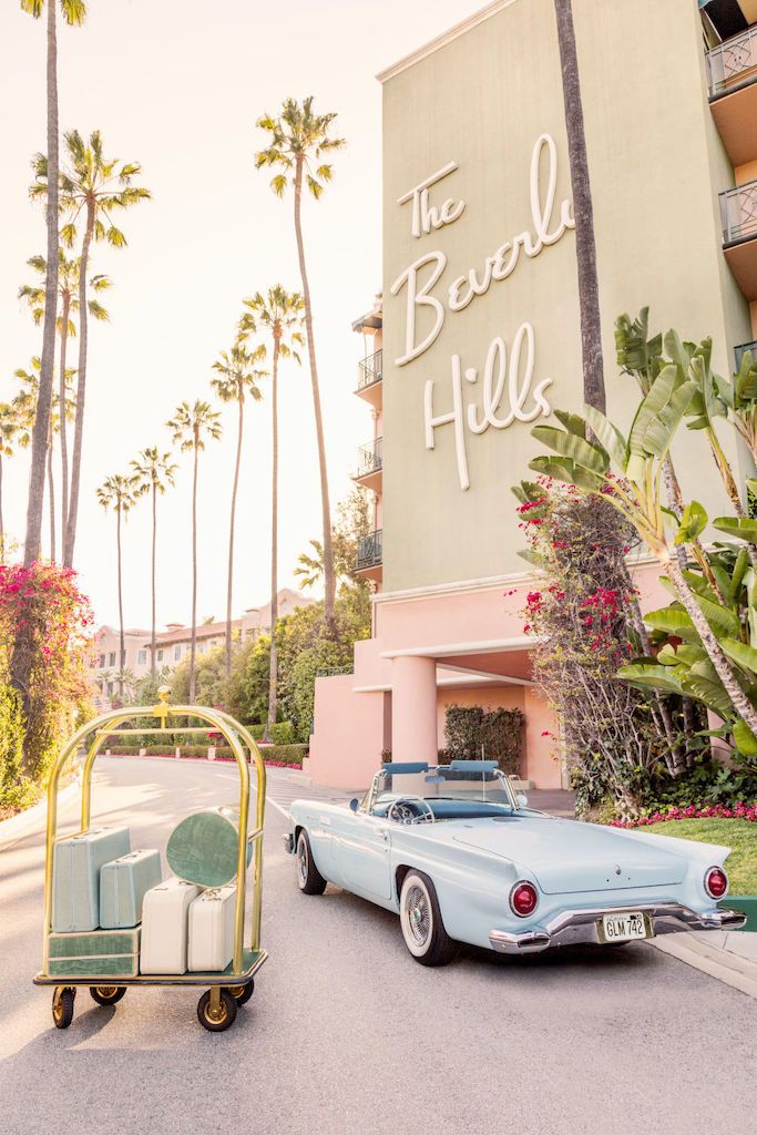 Gray Malin’s "Joy Ride, The Beverly Hills Hotel" (15.5” x 21”, White Frame) features a pale blue vintage convertible and gold luggage cart under palm trees, capturing retro glamour in Gray Malin's iconic style.