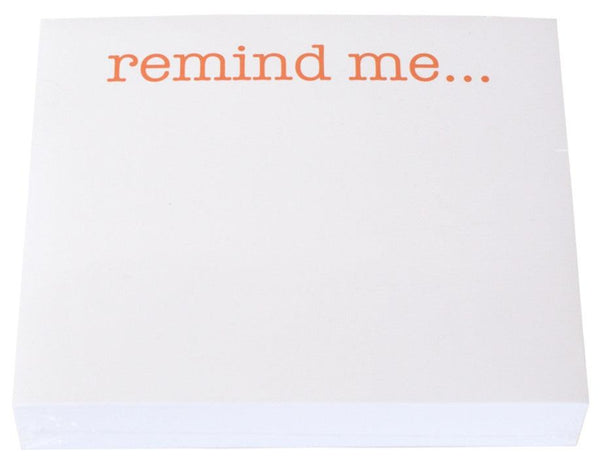 A stack of Black Ink Large Notepads with "remind me..." printed at the top in orange letters, nestled inside a sleek Lucite Notepad Holder.