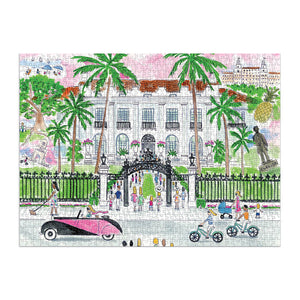 A completed Chronicle Books Michael Storrings A Sunny Day in Palm Beach 1,000 Piece Puzzle depicting a lively scene in front of an elegant building in Palm Beach with people, palm trees, a vintage car, and cyclists.