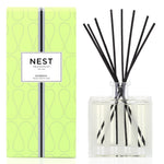 A green box labeled "Nest Bamboo Diffuser" sits beside a clear glass jar with black reeds, ideal for filling your space with lush bamboo scents using Nest’s premium fragrance oils.