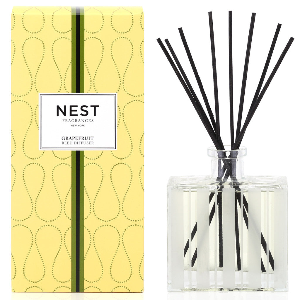 A yellow box labeled "Nest Grapefruit Diffuser" sits beside a clear glass diffuser with black reeds, ideal for adding a luxurious scent to your space.
