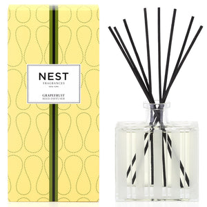 A yellow box labeled "Nest Grapefruit Diffuser" sits beside a clear glass diffuser with black reeds, ideal for adding a luxurious scent to your space.