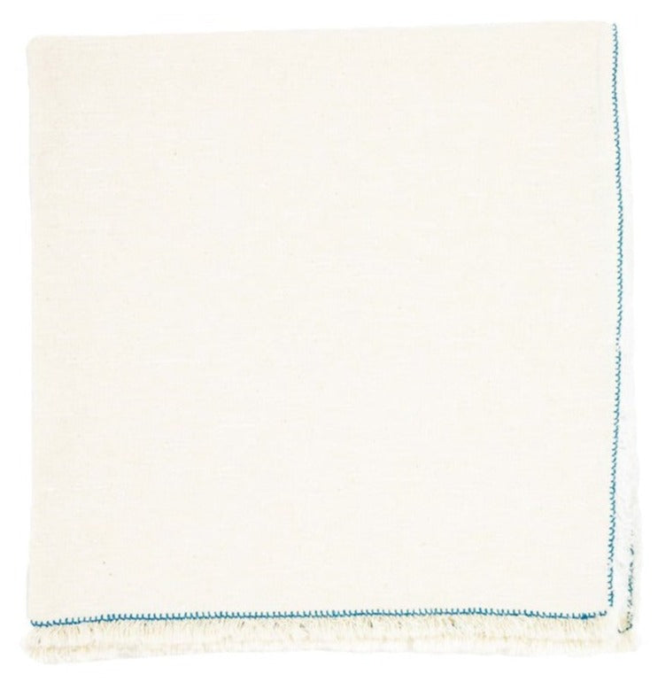 The Deborah Rhodes Nomad Stitch Fringe Napkin Set features folded napkins with white borders and blue stitched edges, perfect for pairing with bold colors or a braided placemat to create a charming table setting.