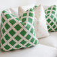A white sofa is adorned with four throw pillows. Two feature a green and white lattice pattern, while the other two have a white background with small orange crosses—each one a handmade, down-filled Petite Cross and Dot Peach Pillow crafted in the USA by Edgar Custom Drapery.