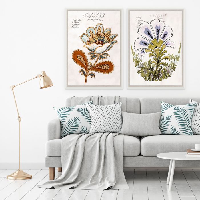 Stylish living room with a gray sofa adorned with patterned pillows reflecting classic French design, a draped blanket, botanical art prints on wall printed on fine art acid-free paper by Natural Curiosities, a Pignier Fleurs 2 in Acrylic Box floor lamp.