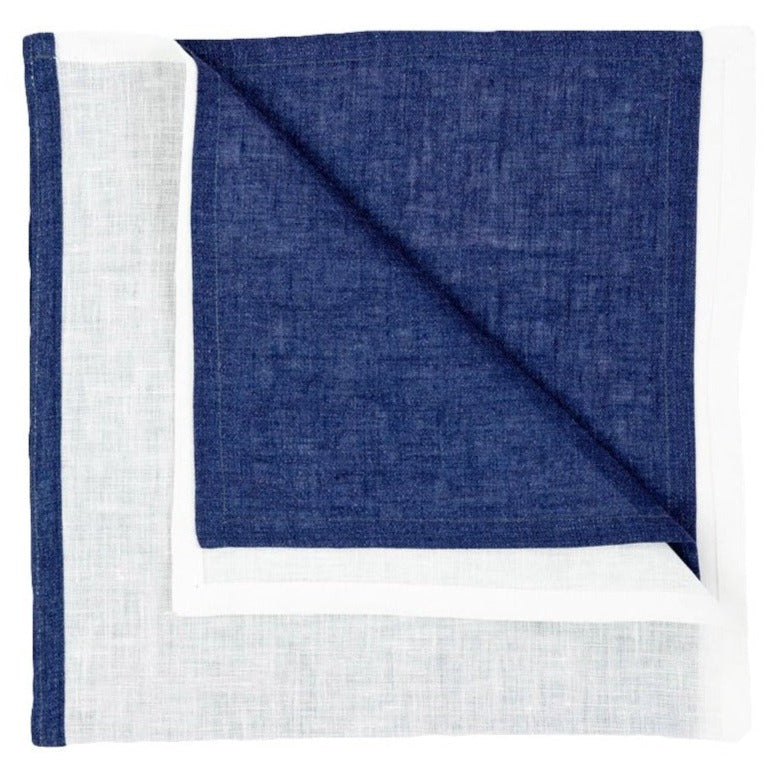 The Deborah Rhodes Resort Two-Tone Napkin Set features neatly folded square linen napkins with a dark blue center and white border—ideal for bringing vibrant summer style to your table.