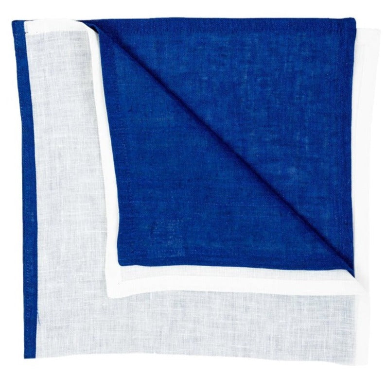 The Resort Two-Tone Napkin Set by Deborah Rhodes features square linen napkins with a blue center, white border, and a folded corner—perfect for adding vibrant color to your summer table.