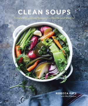 The cover of the Penguin Random House book "Clean Soups" by Rebecca Katz showcases a bowl filled with an assortment of colorful vegetables and includes the subtitle: "Simple, Nourishing Recipes for Health, Vitality, and Detox.