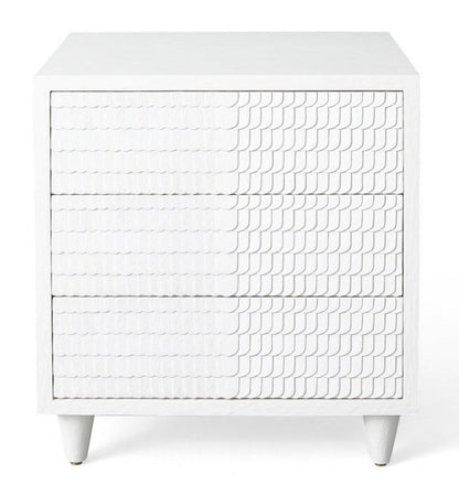 The Lance Bedside Table by Mr Brown is a white piece with three drawers, showcasing a textured wave design and finished in smooth white gesso. Standing at 26.5 inches high, it is ideal for compact spaces and is set against a plain background to accentuate its elegant proportions.