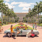 A group and a dog gather around a classic convertible on a palm-lined Palm Beach driveway, bikes leaning casually nearby, echoing the luxury lifestyle vibe seen in Gray Malin's "The Breakers Palm Beach," White Frame, 29.5" x 41.5".