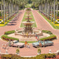 A group gathers by vintage cars and a fountain on the palm-lined main drive in "Gray Malin The Main Drive, The Breakers Palm Beach, White Frame, 24" x 36" by Gray Malin," with manicured gardens and a clear sky.