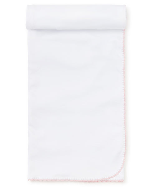 A Kissy Kissy Premier Basics Blanket in white with pink trim, offering unrivaled comfort due to its Pima cotton material.