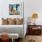 A bedroom featuring Noir's Four Poster Whitewash Venice Bed, Queen, with patterned pillows, a mahogany nightstand and lamp, a bench at the bed's foot, slippers on the floor, and framed artwork on the wall.