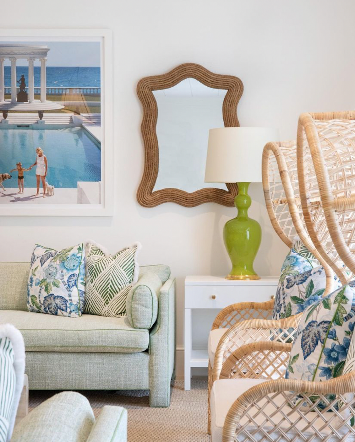 A living room with wicker chairs and a large mirror, featuring a Marjorie Lamp by Christopher Spitzmiller.