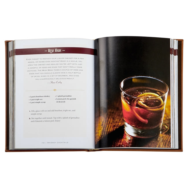 The Whiskey Cocktails Book by Graphic Image, bound in Cognac Leather, displays recipes on the left page and a tempting image of a cocktail with a lemon twist on the right.