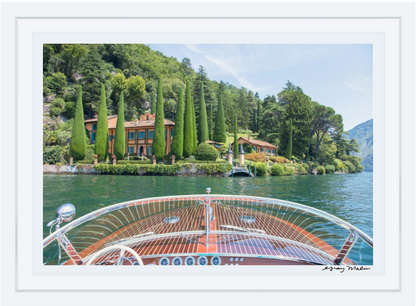 A wooden boat nears a lakeside villa amid cypress trees and greenery on Lake Como, captured in Gray Malin’s "Afternoon Ride Lake Como" (White Frame, 24"x36")—the perfect touch from the Gray Malin collection.