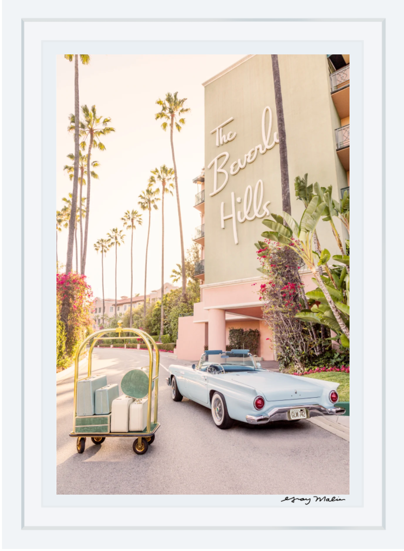 Gray Malin’s “Joy Ride, The Beverly Hills Hotel” features a vintage blue convertible and luggage cart against iconic palm trees, capturing the glamour of Beverly Hills in a 15.5” x 21” white-framed print.